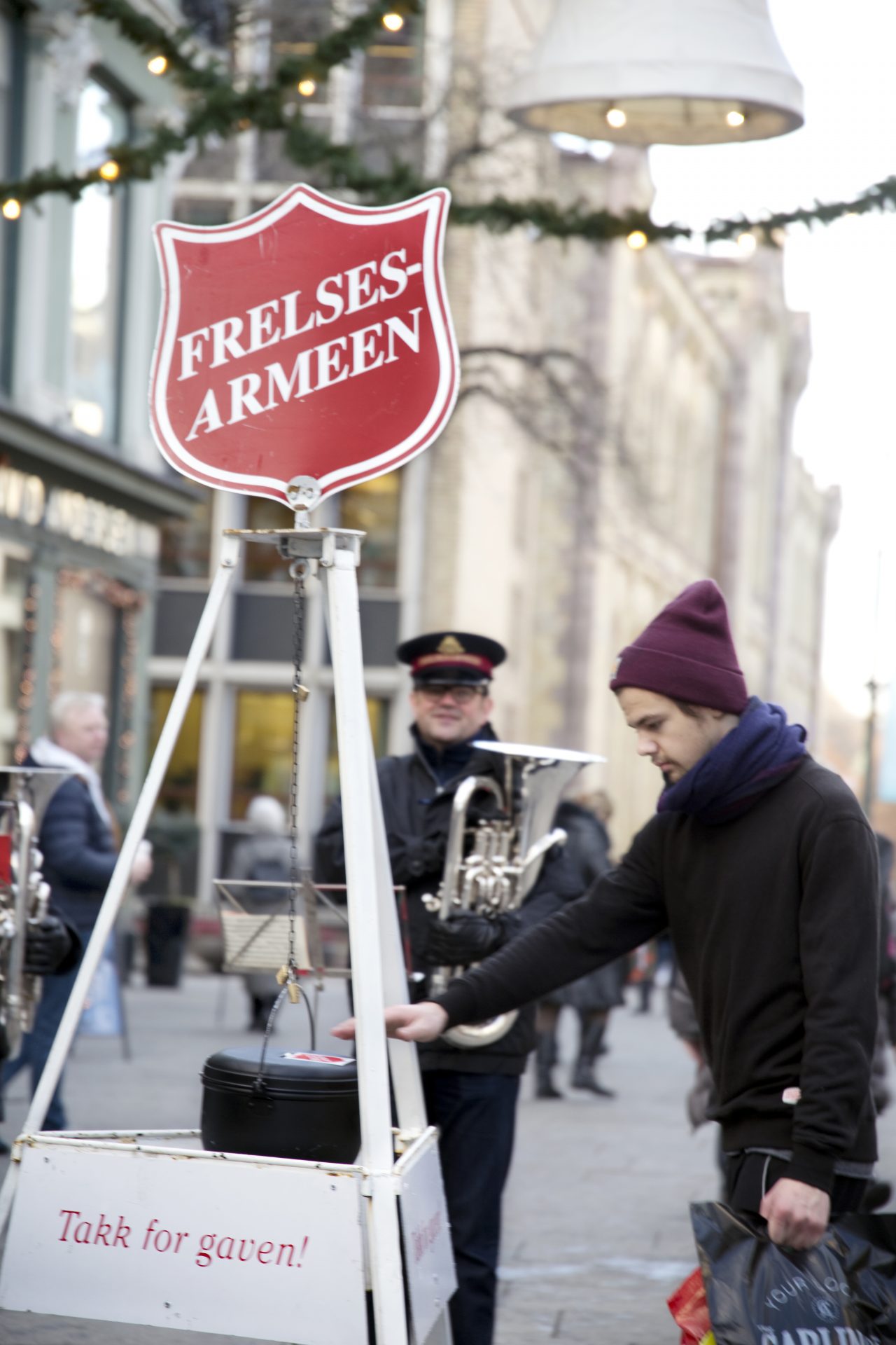 Mann som gir penger til julegryta til Frelsesarmeen på Egertorget