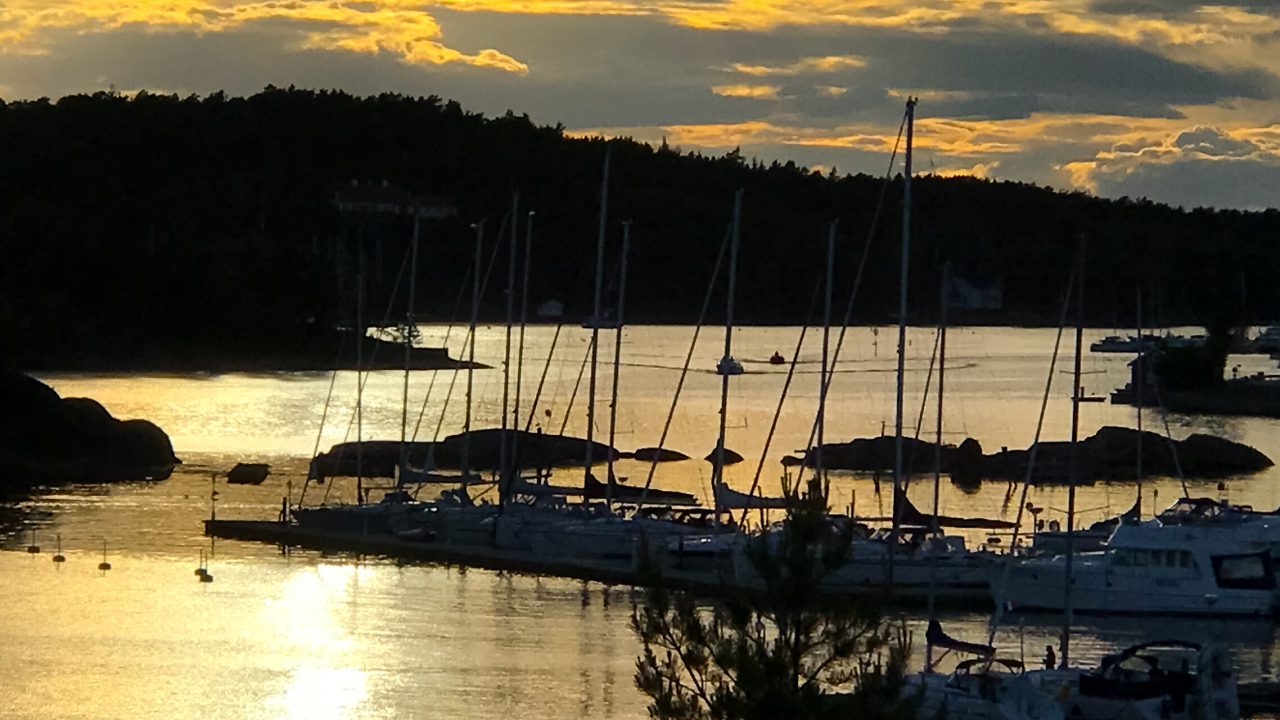 En båthavn med seilbåter i kveldssol.