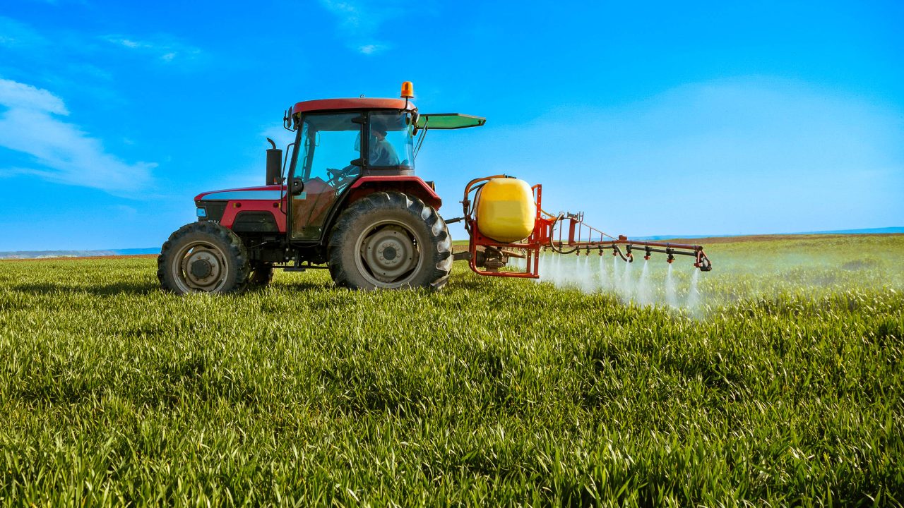 traktor som gjødsler en åker.